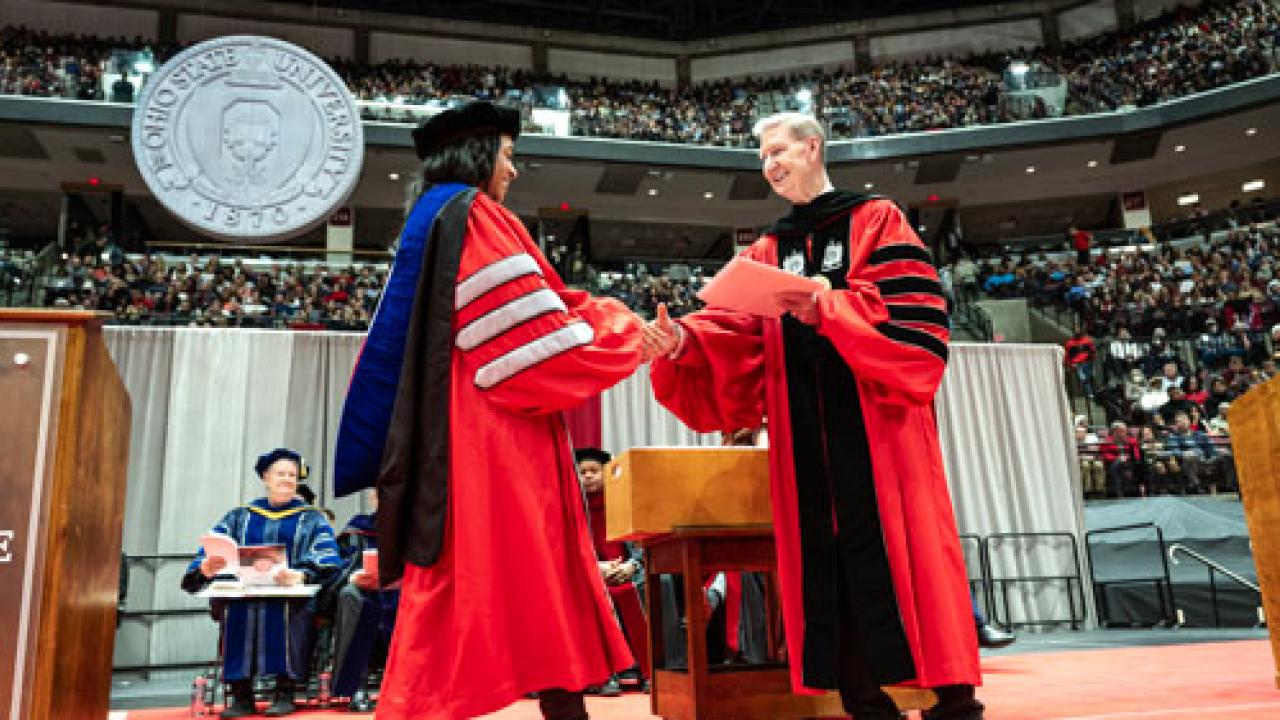 Ohio State President Ted Carter handing a diploma to a new Ohio State graduate